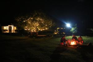 a group of people sitting around a fire at night at Rainbow Residency in Yelagiri