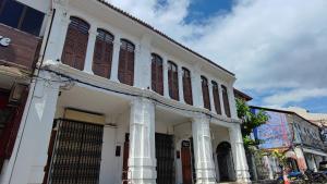 a white building with columns and windows on a street at TREASURE HUNTER At Heritage Georgetown in George Town