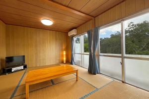 - un salon avec une table en bois et une grande fenêtre dans l'établissement Crystal Inn Onna, à Onna