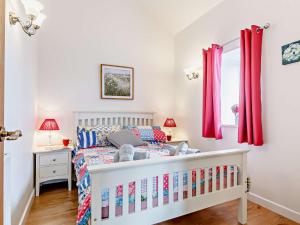 a bedroom with a white crib and red curtains at 2 Bed in Wellington 56950 in West Buckland