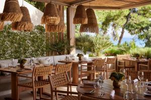 a restaurant with wooden tables and chairs and some plants at Ikos Oceania in Nea Moudania