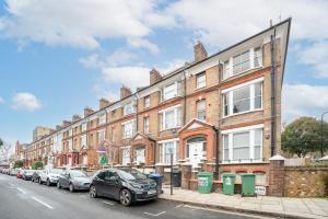 uma fila de edifícios numa rua com carros estacionados em ALTIDO Cosy maisonette near Abbey Road em Londres