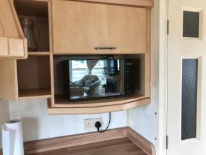 a microwave in a cabinet with a tv in it at No 70 in Newton Stewart