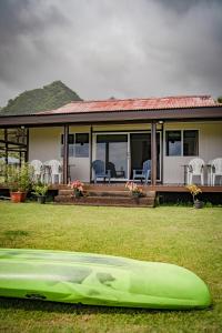 a green kayak on the grass in front of a house at Havae Lodge in Teahupoo