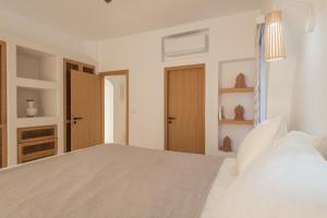 a white bedroom with a white bed and a closet at Sirius Villa Skalia in Skaliá