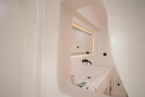a white bathroom with a sink and a mirror at Sirius Villa Skalia in Skaliá