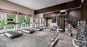 a gym with several treadmills and elliptical machines at Delonix Hotel Karawang in Karawang