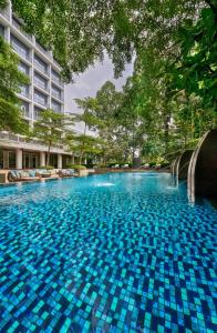 a large swimming pool with blue tiles in front of a building at Delonix Hotel Karawang in Karawang