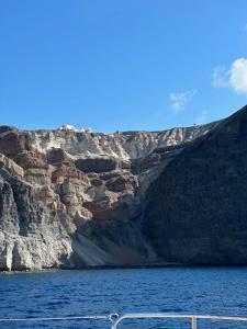 a boat in a body of water next to a mountain at Villa G in Mesaria