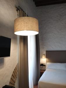 ein Schlafzimmer mit einem Bett und einer großen Lampe in der Unterkunft Hotel Tugasa Convento San Francisco in Vejer de la Frontera