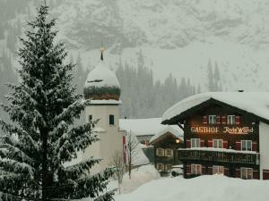 a snow covered christmas tree in front of a building at Walch's Rote Wand Gourmethotel in Lech am Arlberg