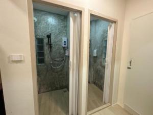 a bathroom with a shower with a glass door at NooN23 Hostel in Chiang Mai