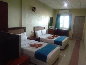 ein Hotelzimmer mit 2 Betten und einem TV in der Unterkunft Arwana Inn Tok Bali in Pasir Puteh