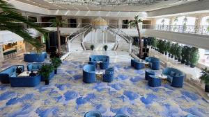 ウルムチ市にあるグランド メルキュール ホテル ホアリングの青い椅子と階段のある広いロビー