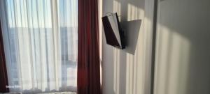 uma televisão pendurada numa parede ao lado de uma janela em Apartament Lucian em Râmnicu Vâlcea