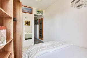 ein weißes Schlafzimmer mit einem Bett und einem Flur in der Unterkunft Appart pour 4 dans domaine avec piscine in Noirmoutier-en-l'lle