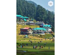 a group of people in a grassy field with houses at Parul Hotel and restaurant,Khajjiar in Khajjiar 