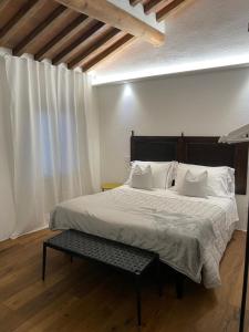 a bedroom with a large white bed with a bench at MontepulcianoLettings in Montepulciano