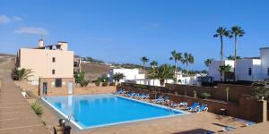 a large swimming pool with lounge chairs next to a building at Casa Felix - Ferienwohnung in Esquinzo in Playa Jandia