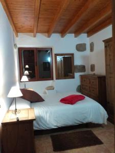 a bedroom with a white bed with a red pillow at Casa Rural Carmita in Vega de San Mateo