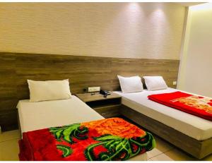 Habitación con 2 camas y manta roja. en Bajaj Regency, Ludhiana, en Ludhiana