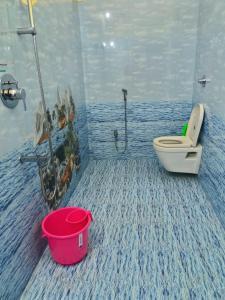 a blue bathroom with a toilet and a bucket at VJ VILLA HOME STAY PURPLE ROOM in Puducherry +2 photos