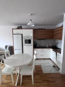 - une cuisine blanche avec une table et des chaises blanches dans l'établissement Krynica Zdrój Apartament 4 pokoje, à Krynica-Zdrój