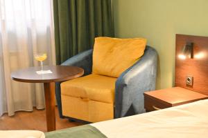 a room with a chair and a table with a wine glass at Hotel Ida in Bansko