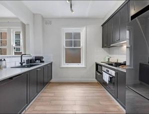 a large kitchen with black cabinets and a window at Cozy King Suite Millers Point in Sydney