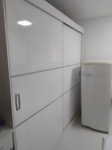 a kitchen with white cabinets and a refrigerator at Studio Gru in Guarulhos