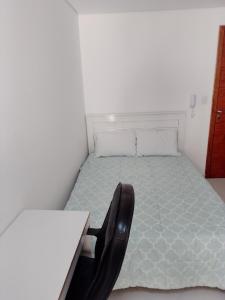 a bedroom with a bed with a desk and a chair at Studio Gru in Guarulhos