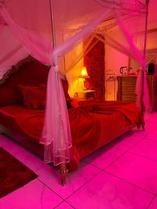 a bedroom with a red bed with pink lighting at Suite romantique avec jaccuzy à la gare de Montpellier in Montpellier