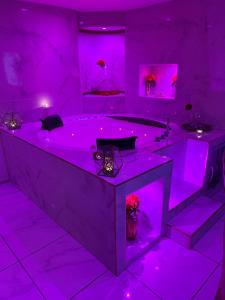 uma casa de banho roxa com uma grande banheira com iluminação roxa em Suite romantique avec jaccuzy à la gare de Montpellier em Montpellier