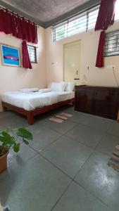 - une chambre avec un grand lit et des rideaux rouges dans l'établissement Wow Farm House, à Auroville