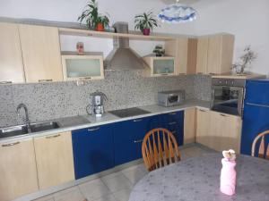 eine Küche mit blauen Schränken und einem Tisch mit einem kleinen Mädchen in der Unterkunft Casa Crevatini in Koper