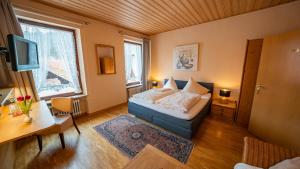 a bedroom with a bed and a desk and a television at Hotel Restaurant St. Germanshof in Bobenthal