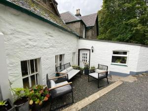 a patio with furniture and a white building at Knockfarrie Cottage in Pitlochry