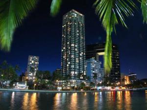 eine Skyline der Stadt in der Nacht mit einem hohen Gebäude in der Unterkunft Waikiki Ocean View Penthouse 2/2 bdr/bath in Honolulu