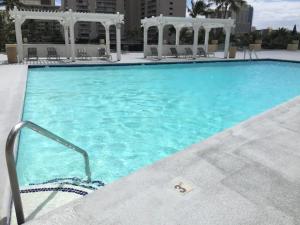 a large swimming pool with blue water and white gazebos at Waikiki Ocean View Penthouse 2/2 bdr/bath in Honolulu