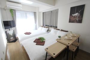- une chambre avec un grand lit blanc et une table dans l'établissement LUANA in SHIBUYA, à Tokyo