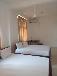 two beds in a room with a window at Vintop Hotel & Homestays Gampaha in Gampaha