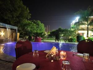 a table with plates of food and a pool at night at Shivhari Hotel & Resort in Gwalior