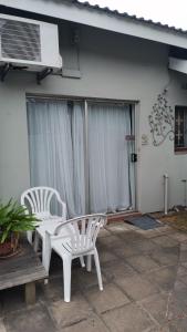 two white chairs sitting on a patio in front of a house at Dreamers nest in Richards Bay