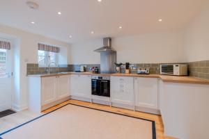 a large kitchen with white cabinets and appliances at Deer Park Farmhouse in Lydney