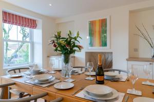 a dining room with a wooden table with a bottle of wine at Deer Park Farmhouse in Lydney
