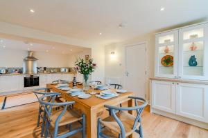 a kitchen and dining room with a wooden table and chairs at Deer Park Farmhouse in Lydney