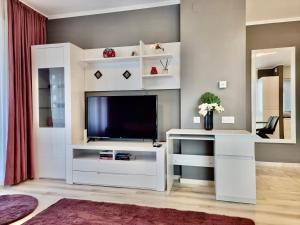 ein Wohnzimmer mit einem TV und einem weißen Entertainment-Center in der Unterkunft Near Forest in Timişoara