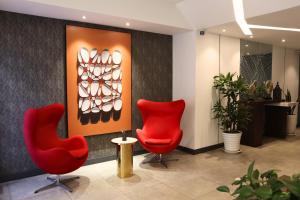 a lobby with two red chairs and a painting of glasses at CDX RESIDENCE in Phnom Penh