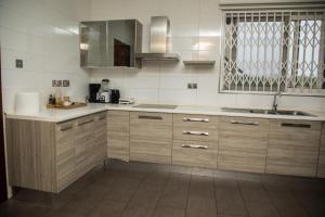 una cocina con armarios de madera y fregadero en Ridge Cozy Rooms en Accra