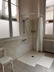 a shower in a bathroom with a chair and windows at Le manoir de la Cane in Montfort-sur-Meu